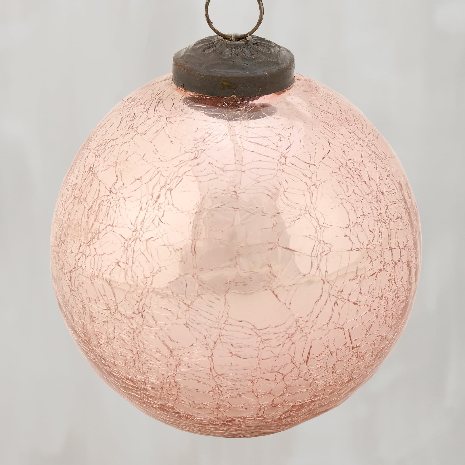 A delicate pink ball glass ornament with crackled texture and dark metal cap perfect for christmas decor