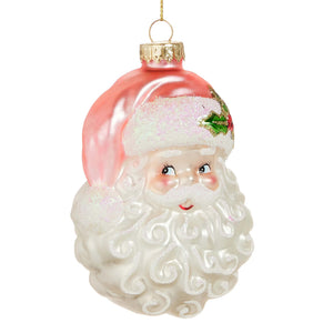 Pink santa head ornament made of translucent glass with white textured beard and hat decorated with green holly
