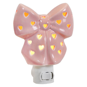 Pink valentine’s day night light shaped like a ceramic bow with heart cutouts glowing warm orange