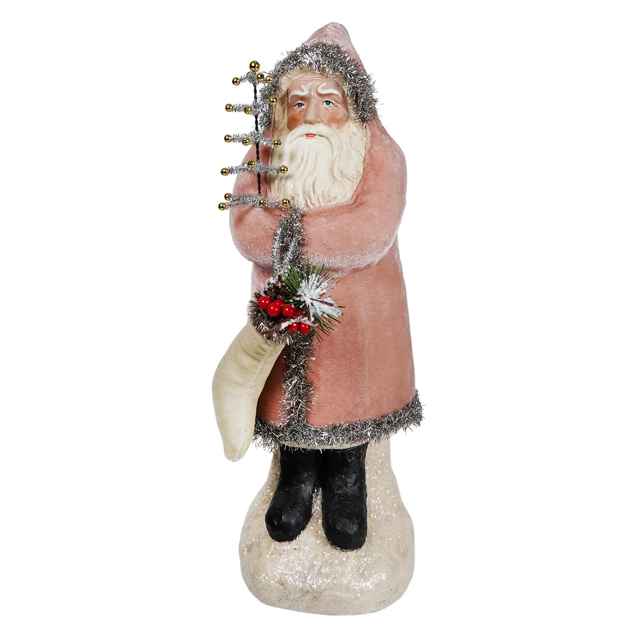 A vintage velvet belsnickle figurine in a pink coat with silver tinsel trim holding a tree on a snowy base with stocking