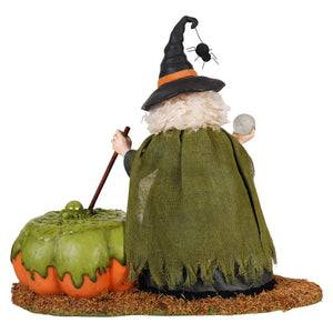 A whimsical poison brewing pruella witch figurine with a black hat, white curly hair, burlap cape, broomstick, and pumpkin cauldron