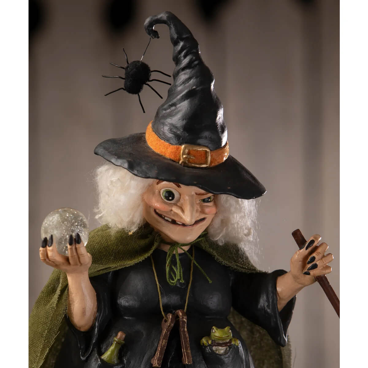 A whimsical black witch figurine with white curly hair holding a glittering orb from poison brewing pruella