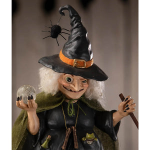 A whimsical black witch figurine with white curly hair holding a glittering orb from poison brewing pruella