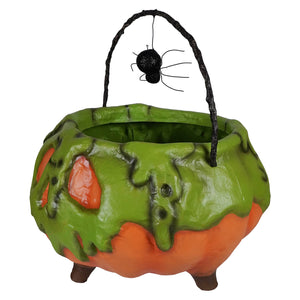 Green and orange poison pumpkin cauldron with a black spider hanging from its handle for halloween decor