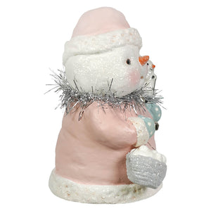 A pretty in pink snowgirl snowman figurine with glittery white hat and scarf holding silver tinsel from bethany lowe designs