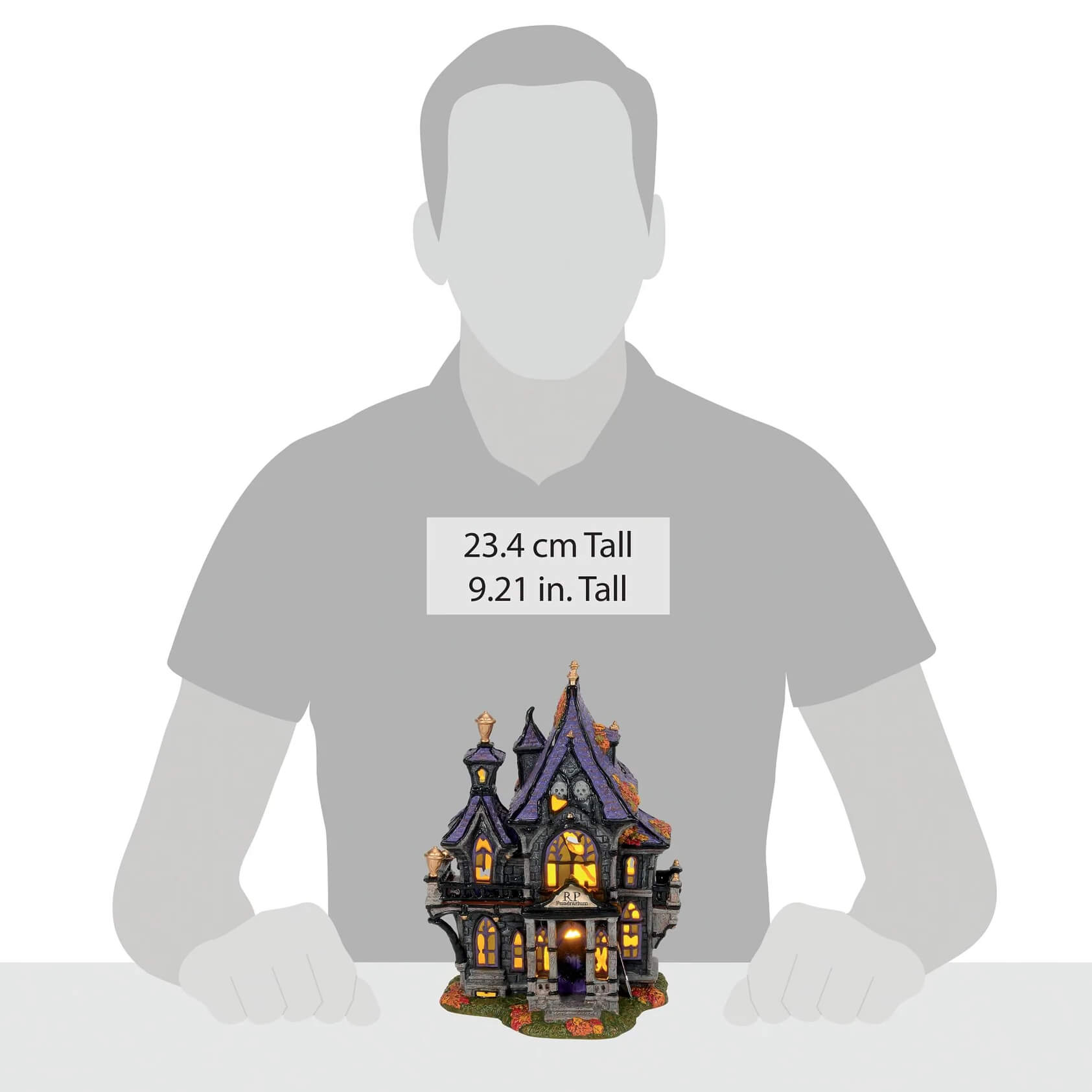 A miniature haunted house figurine from puckett’s funerarium with dark purple roof, stone walls, glowing lights, and pumpkins