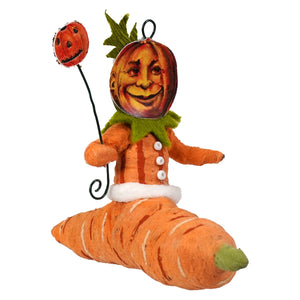 Orange pumpkin-faced spun cotton black krampus freestand ornament with green collar and white buttons on carrot canoe