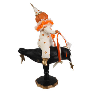 A whimsical halloween clown figurine in white polka dot with orange ruffles riding a black crow with star charms