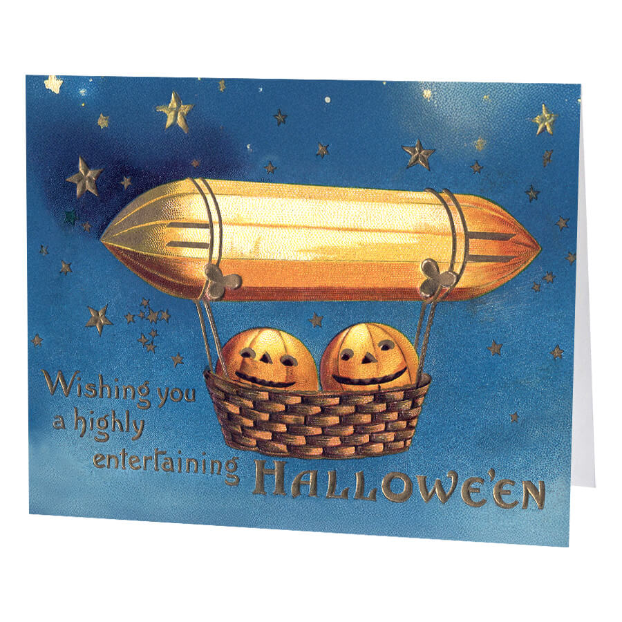 Golden airship greeting card with black straps and woven basket holding two smiling orange pumpkins in starry sky