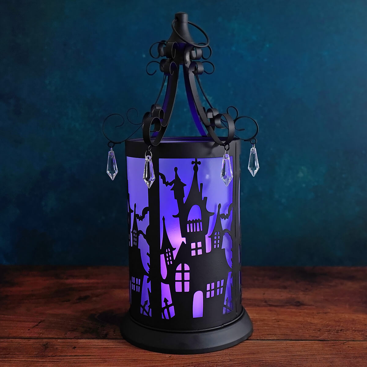 Halloween-themed decorative lantern with a purple light and silhouettes of spooky houses and figures.