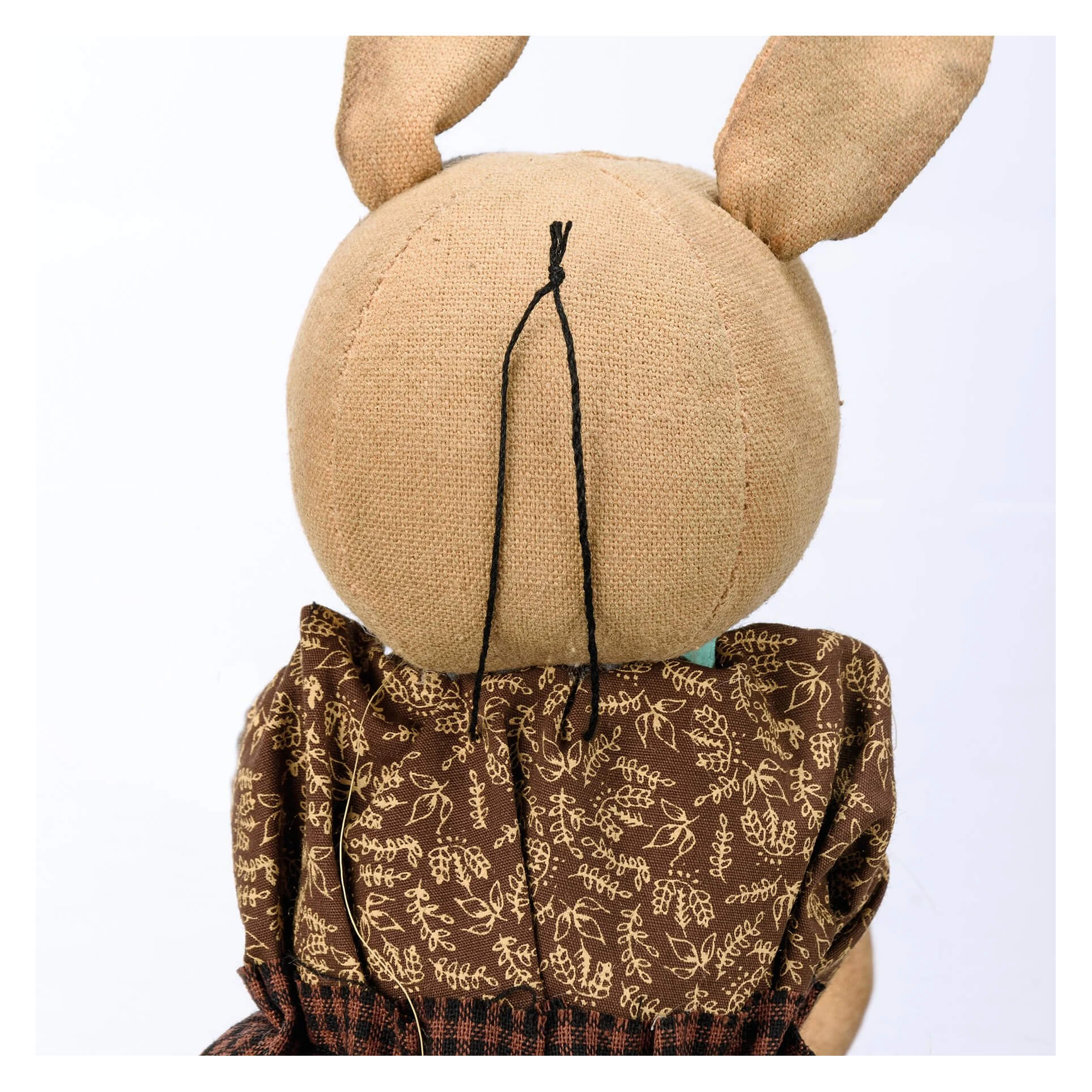 Handmade plush rabbit egg doll with tan burlap ears and head wearing brown dress with beige leaf patterns