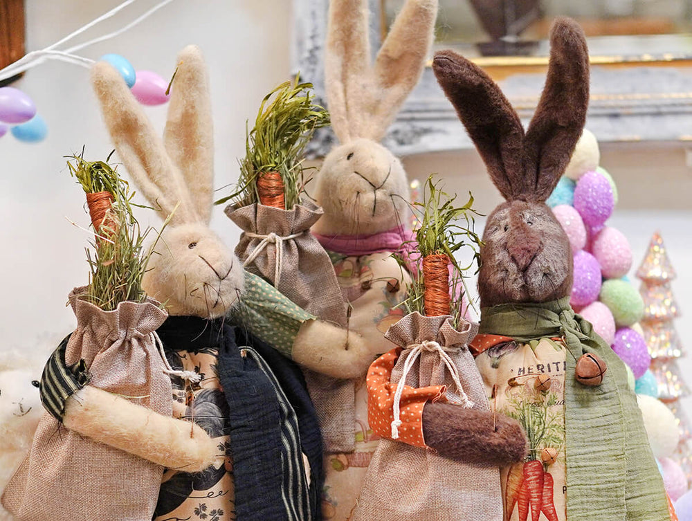 Three plush toy bunnies with carrot accessories in a decorative setting with balloons.