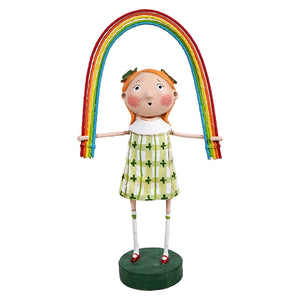 Whimsical figurine wearing a green patterned dress while holding up a colorful rainbow arch.