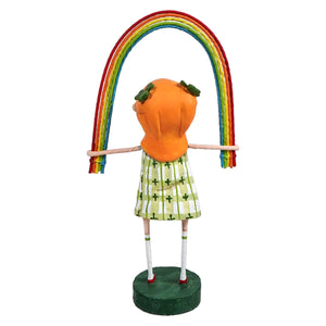 Whimsical figurine of a character in an orange top and patterned skirt holding up a colorful rainbow.