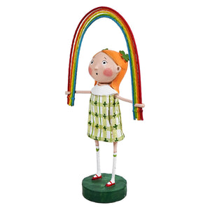 Whimsical figurine holding a colorful rainbow arch while wearing a green patterned dress.