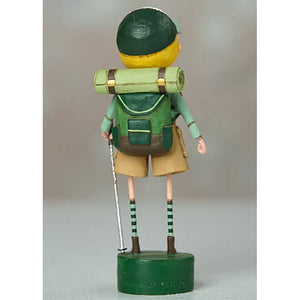 Wooden toy figure wearing green clothing, a backpack, and striped socks on thin legs.