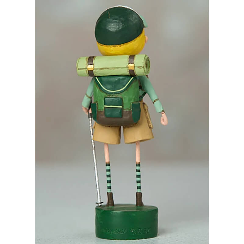 Wooden toy figure wearing green clothing, a backpack, and striped socks on thin legs.