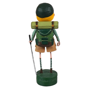 A whimsical green and yellow ranger rick hiking figurine with striped socks, backpack, and walking stick from lori mitchell patriotic figures