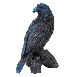 A detailed iridescent blue and black raven figurine with gothic charm perched on a textured tree stump base