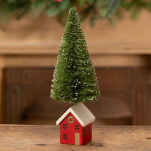 A red wooden miniature house with white roof and green bottle brush tree topped with snowflakes vintage christmas village trees