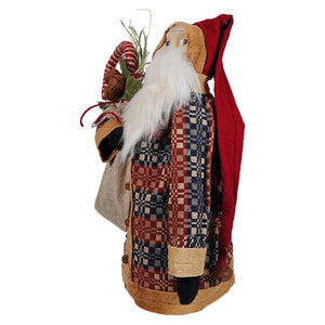 A rustic raggedy junction santa figure with a long white beard wearing red hat and plaid coat holding a stocking