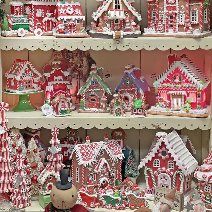 Display of colorful gingerbread houses and Christmas trees on a shelf.
