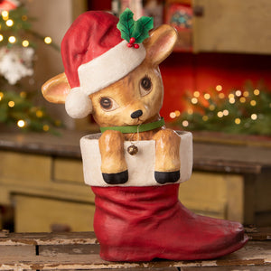 A bethany lowe design reenie reindeer ceramic figurine with a red santa hat peeking from a glossy red stocking