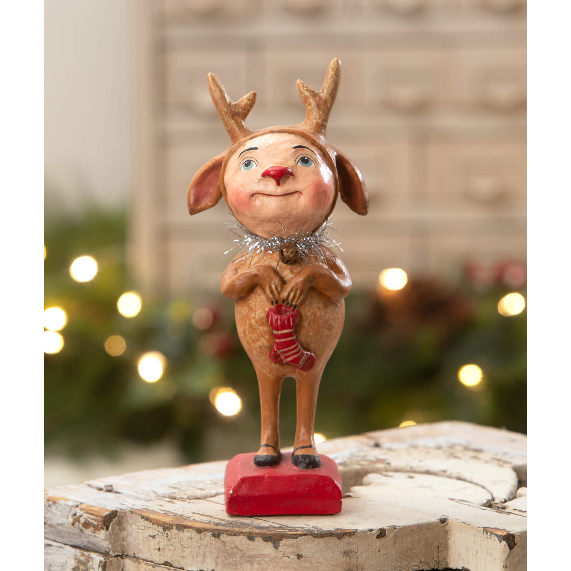 A charming brown ceramic reindeer boy figurine with blue eyes red nose silver collar holding a red striped sock by bethany lowe designs spreading holiday cheer