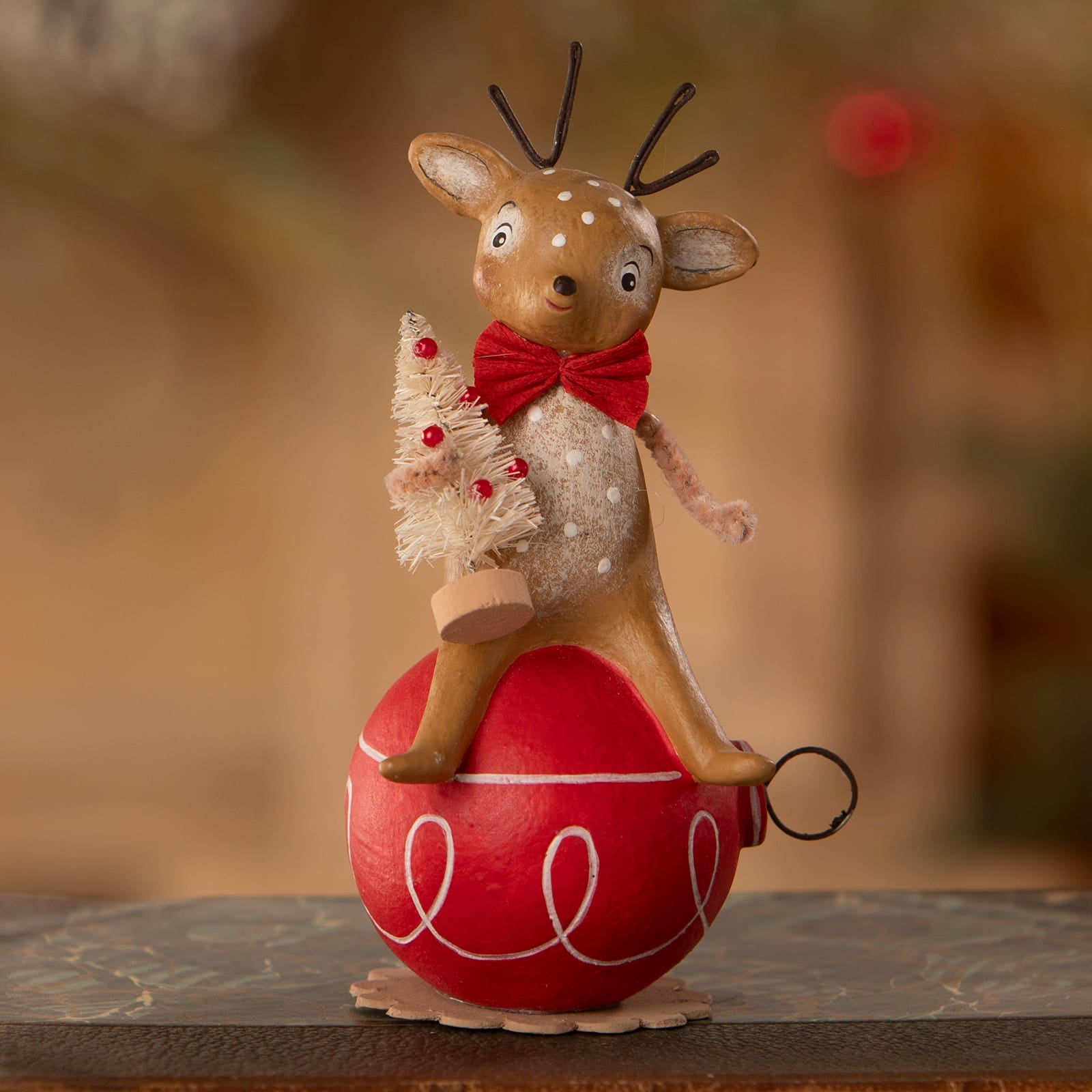A charming wooden reindeer ornament from bethany lowe designs with a red polka dot bow tie holding a mini christmas tree