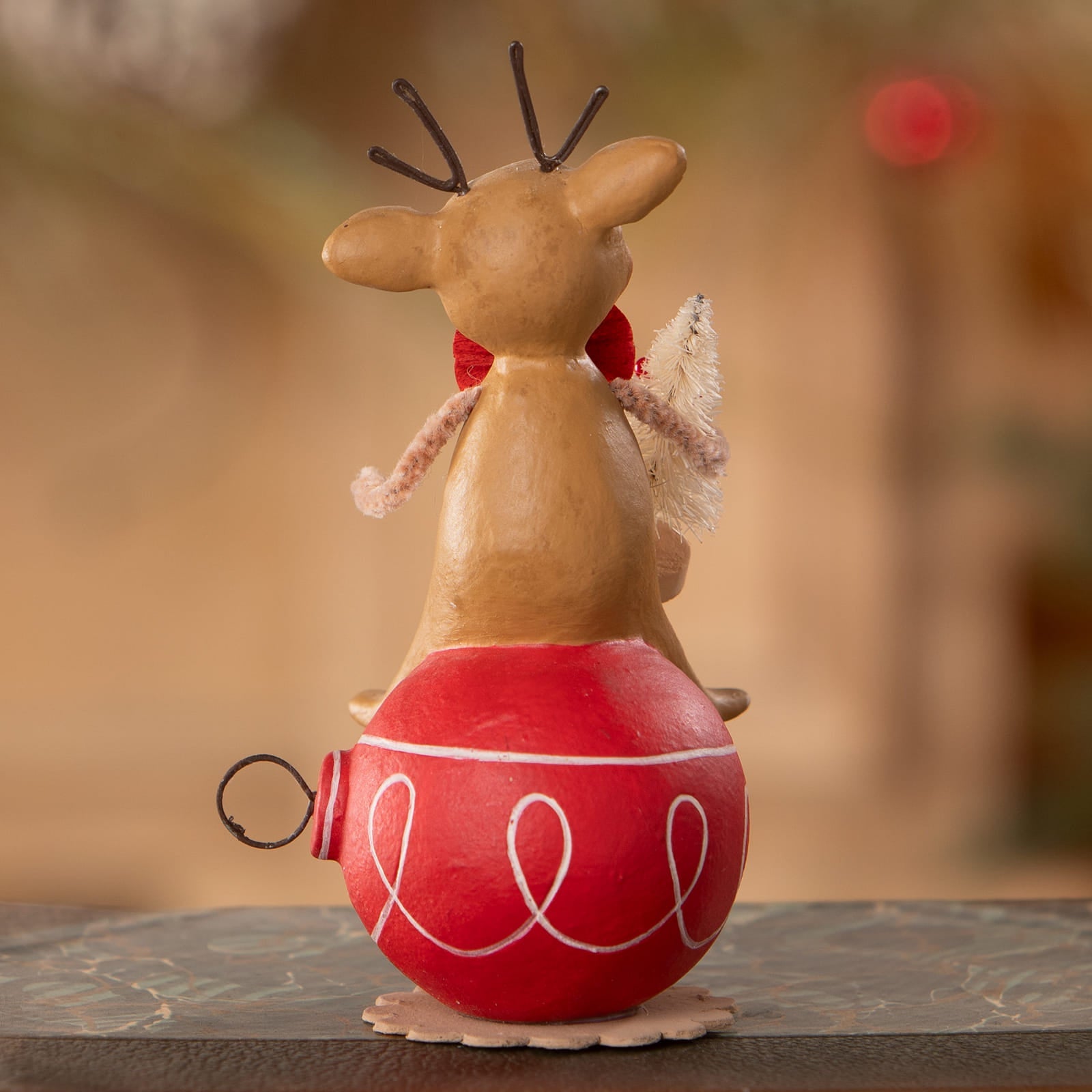 A charming beige reindeer figurine with black antlers and red scarf on a glossy red ornament from bethany lowe designs christmas reindeer figures ornaments & decor