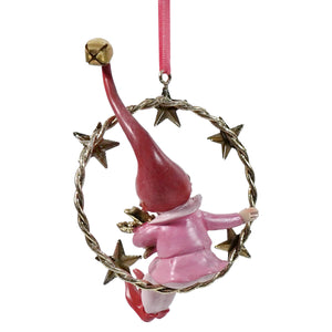 A resin swinging pixie gnome with a long red hat sits inside a twisted gold finish ornament wreath with stars