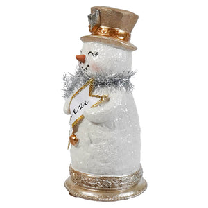 A glittery white resin tinsel snowman figurine with a gold top hat and silver scarf holding a golden star sign