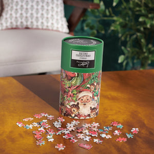A green cylindrical container with a retro christmas puzzle featuring santa and deer labeled prima kelly on the lid