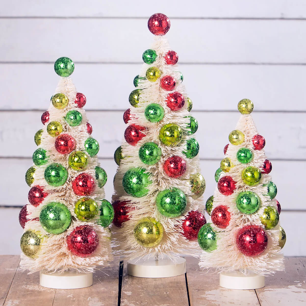 Decorative Christmas trees made of colorful glass ornaments and white fluffy material.