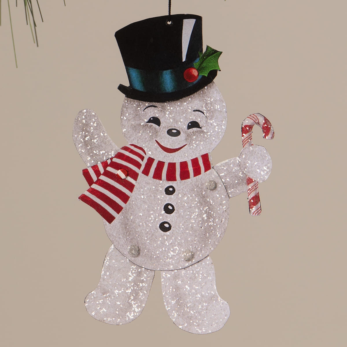 A glittery silver bethany lowe design retro rockin snowman ornament wearing a black top hat holding a candy cane