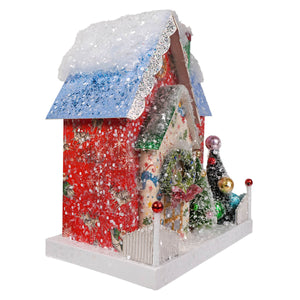 A festive red and blue glittery retro santa adobe christmas house ornament with snow roof and light cord by cody foster