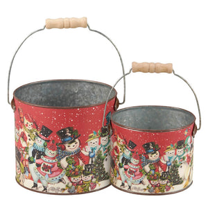 Two decorative Christmas-themed metal buckets with wooden handles and colorful snowman designs.