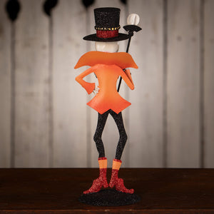 Glittery orange and black ringmaster skeleton decor figure wearing a top hat holding a cane with a skull handle