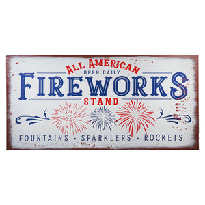 Vintage-style metal sign advertising ’All American Fireworks’ with red, white and blue text and firework burst designs.