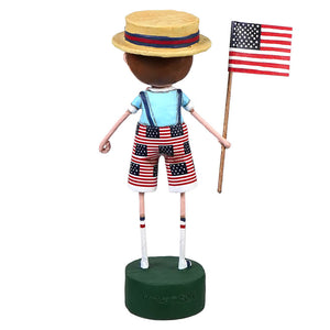 A hand-painted resin lori mitchell patriotic figure of a boy in star and stripes overalls holding an american flag