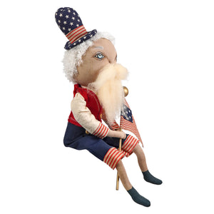 A plush uncle sam doll with a white beard wearing a star-spangled hat and red and white striped sleeves from samuel liberty