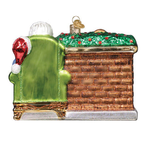 Green glass christmas glass ornament santa ornament showing santa on couch by brick fireplace with green roof and red berries