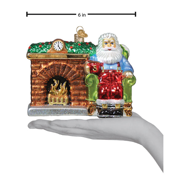 Glass christmas ornament featuring santa ornament in red suit on green armchair by fireplace with clock above