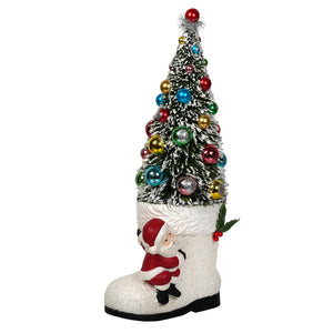 A bethany lowe design santa boot in white glitter with a festive tree ornament and miniature santa figure at the base