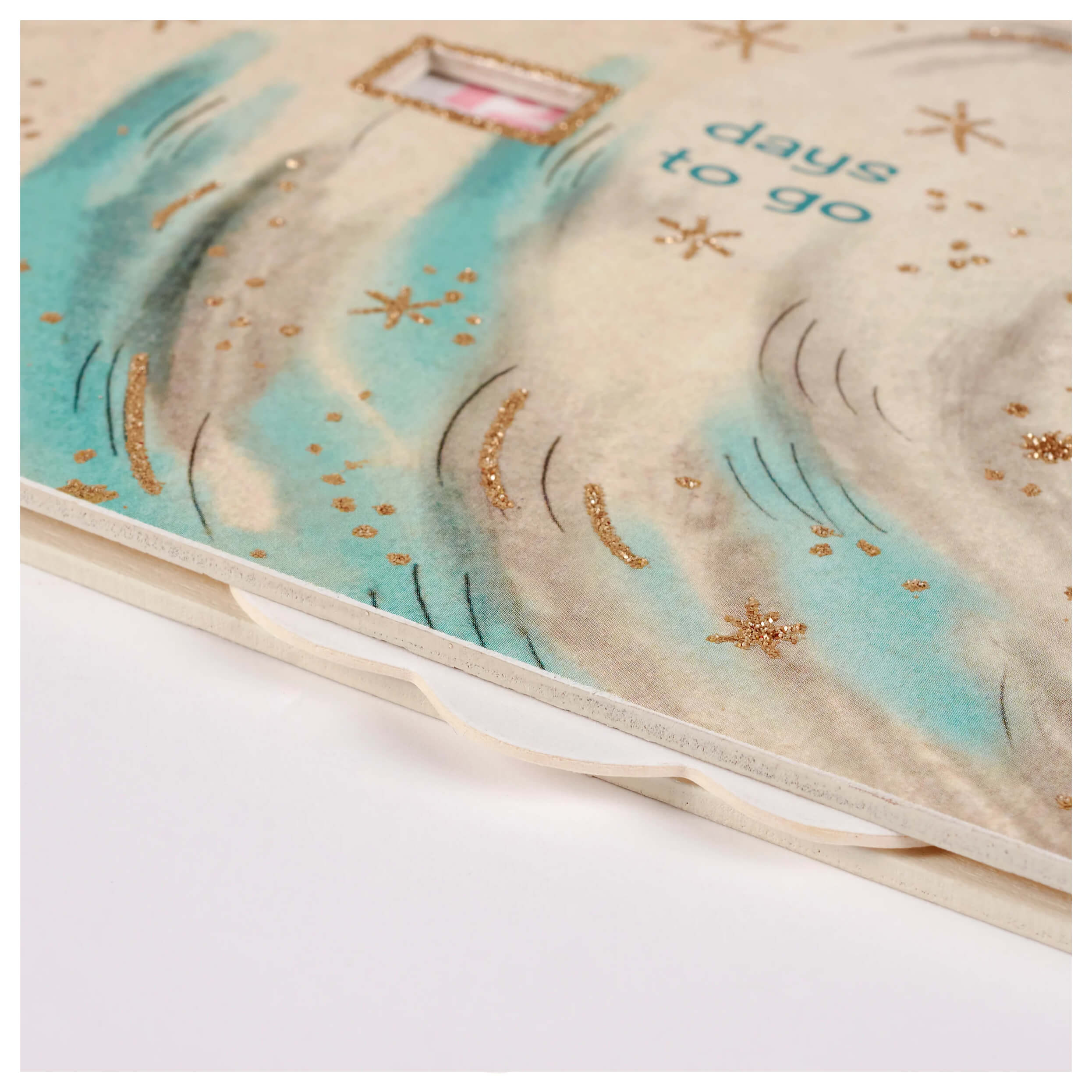 A soft cream pastel christmas countdown journal with teal waves gold glitter stars and days to go script for christmas hanging decor