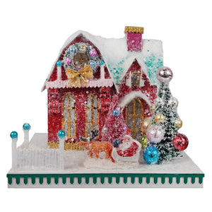 A festive red and gold glittery cody foster christmas house ornament with snow-dusted roof and santa in his sleigh