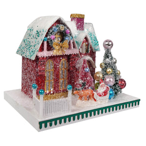 A festive cody foster christmas house figurine in red and gold glitter with a snow-dusted roof and a decorated wreath