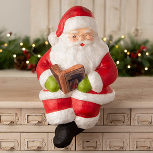 Red and white bethany lowe design santa shelf sitter figurine with green gloves holding a small book for holiday decor