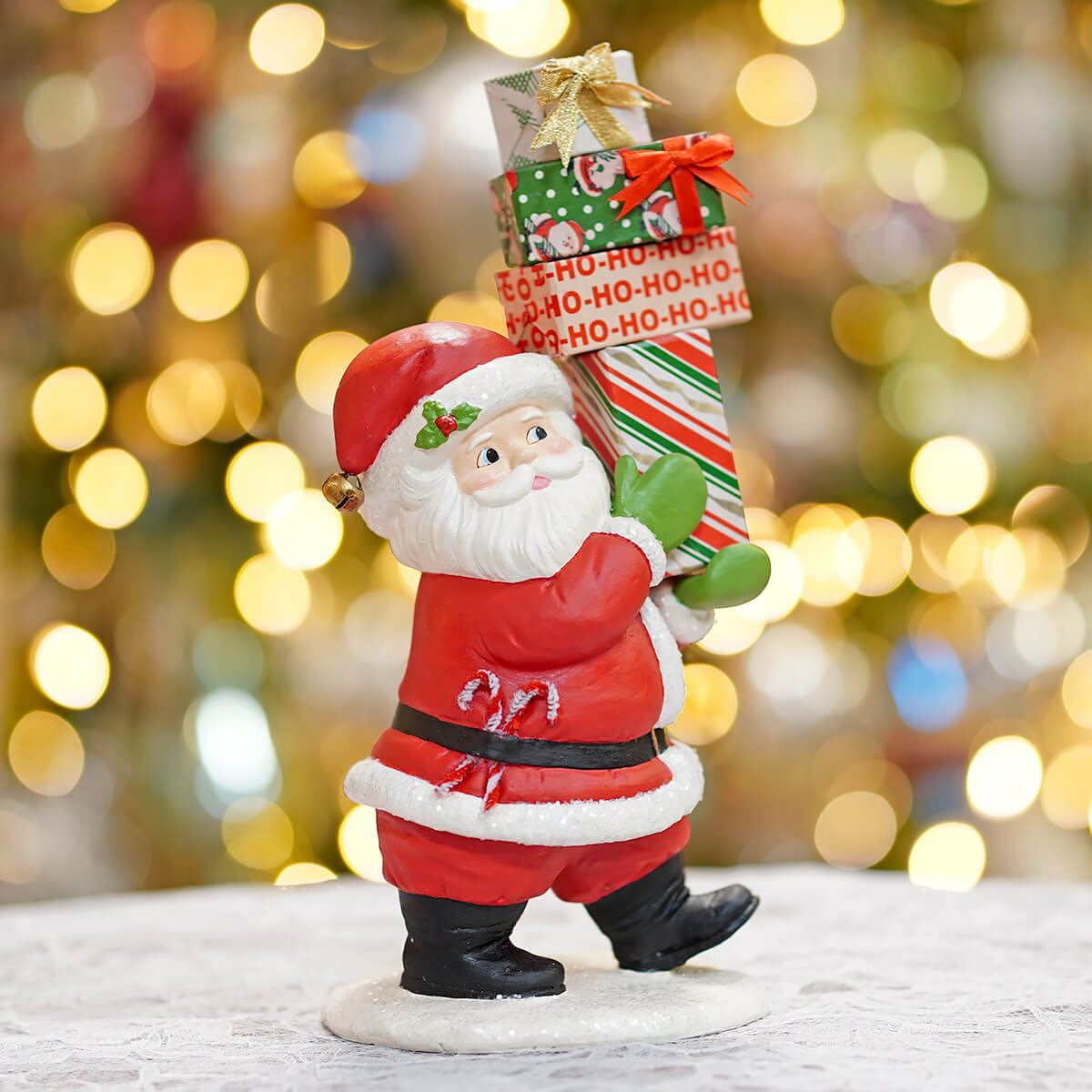 Red and white santa claus figurine carrying holiday-themed gifts from bethany lowes santa’s delivery collection