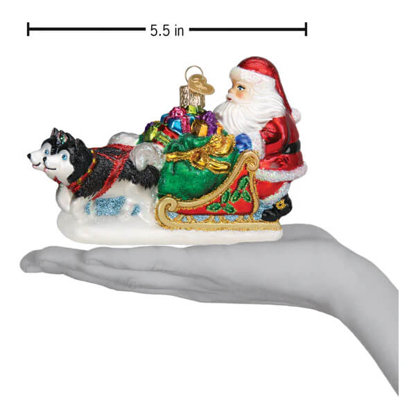 Glass santa’s dog sled ornament features a black and white husky pulling a red sleigh filled with colorful gifts and glitter accents